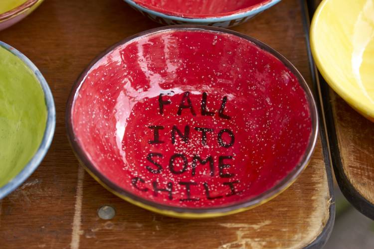 a ceramic bowl with a red bottom. View from above. The inside of the bowl says "fall into some chili"