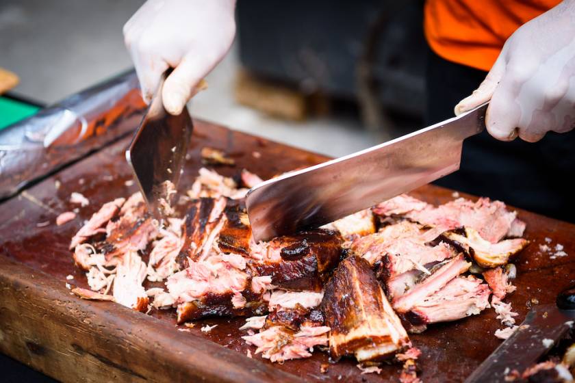 Person chopping BBQ on a cutting board